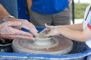 A young boy tries his hand at making a pot on the wheel